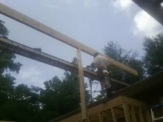 Carpenter setting a ridge beam over a new addition frame — Ice Dam Removal by Roofing Brothers in Hustle