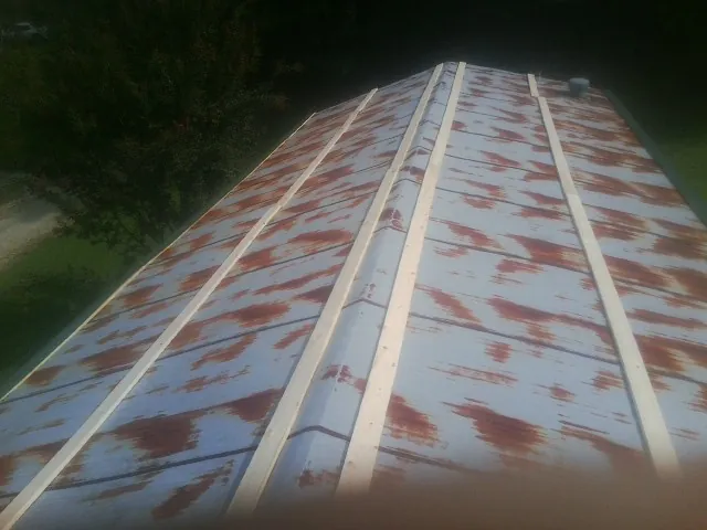 Rusted metal roof panels with new wood purlins before replacement — Storm Damage Roof Repair in Hustle by Roofing Brothers
