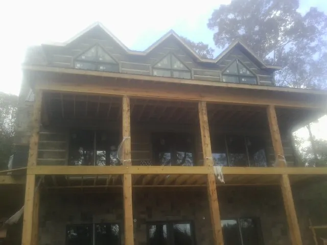 Dormers and porch framing on a large log home under construction — Roof Coating work by our crew in Hustle