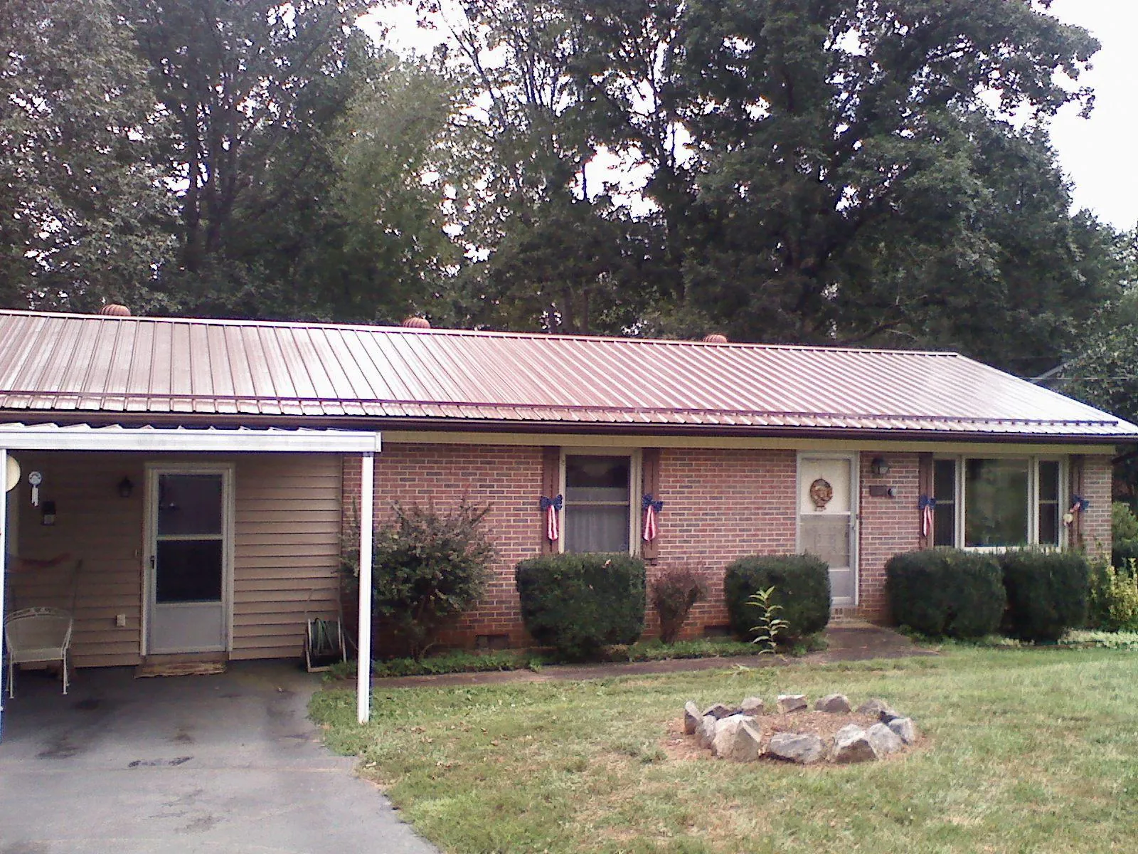 Bronze metal roof and carport on a brick ranch home — Roof Repair work by our crew in Hustle