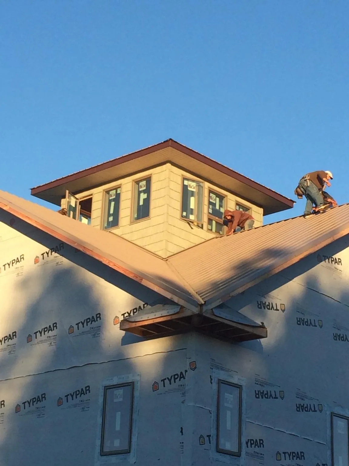 Roofers working around a rooftop cupola on a new metal roof at sunset — Roof Waterproofing in Hustle by Roofing Brothers